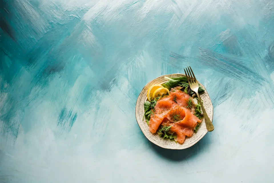 Plato de salmón con hojas verdes y limón sobre el fondo azul original